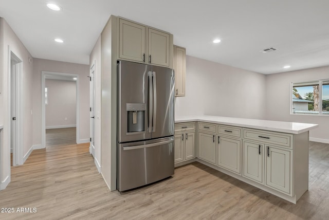 kitchen with light wood-type flooring, kitchen peninsula, and stainless steel fridge with ice dispenser