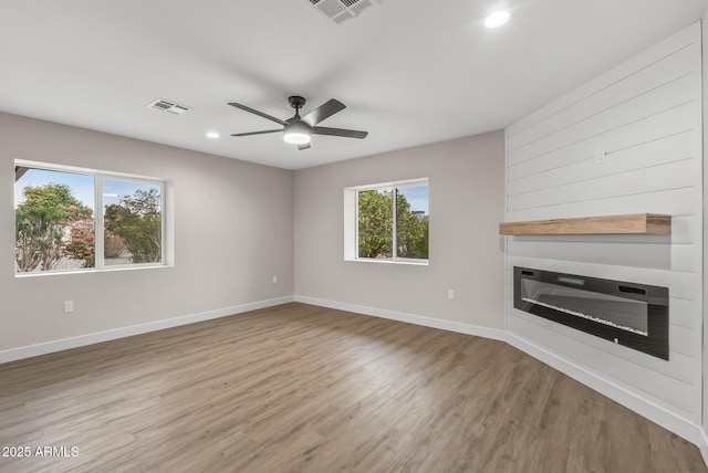 unfurnished living room featuring heating unit, ceiling fan, and wood-type flooring