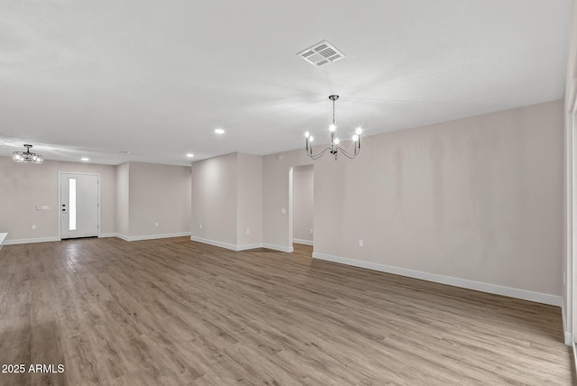 spare room featuring light hardwood / wood-style floors and a notable chandelier