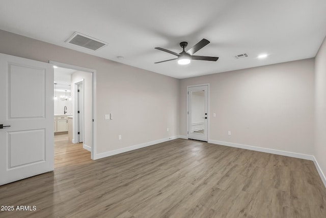 unfurnished room featuring sink, light hardwood / wood-style floors, and ceiling fan with notable chandelier