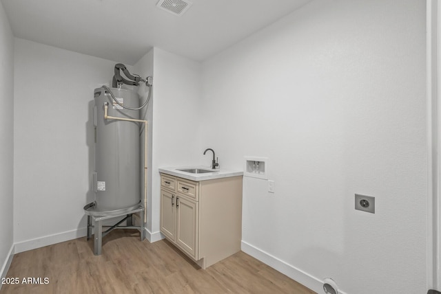 clothes washing area featuring cabinets, hookup for an electric dryer, light hardwood / wood-style flooring, water heater, and sink