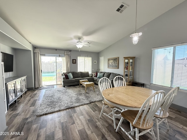 dining space with baseboards, visible vents, a ceiling fan, dark wood-style floors, and high vaulted ceiling