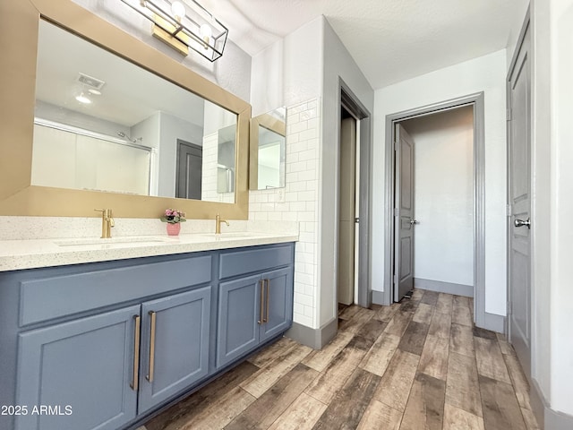 bathroom with double vanity, wood finished floors, a sink, and visible vents