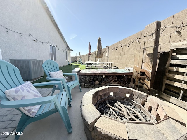 view of patio featuring an outdoor fire pit, central AC, and a fenced backyard