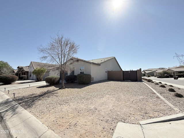 view of property exterior with a residential view, a tile roof, fence, and stucco siding