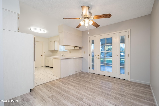 kitchen with white cabinetry, sink, light hardwood / wood-style floors, and a textured ceiling