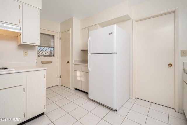 kitchen with white cabinetry, light tile patterned flooring, extractor fan, and white refrigerator