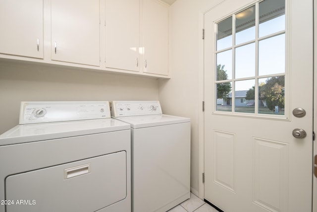 clothes washing area with cabinets, light tile patterned floors, and washing machine and clothes dryer