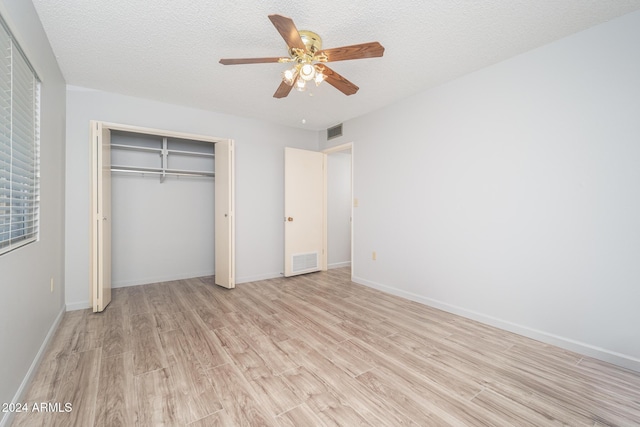 unfurnished bedroom featuring ceiling fan, a closet, a textured ceiling, and light wood-type flooring