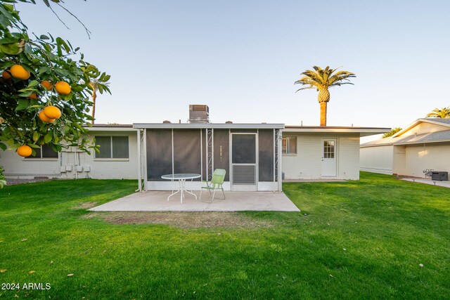 rear view of property with a sunroom, a yard, and a patio