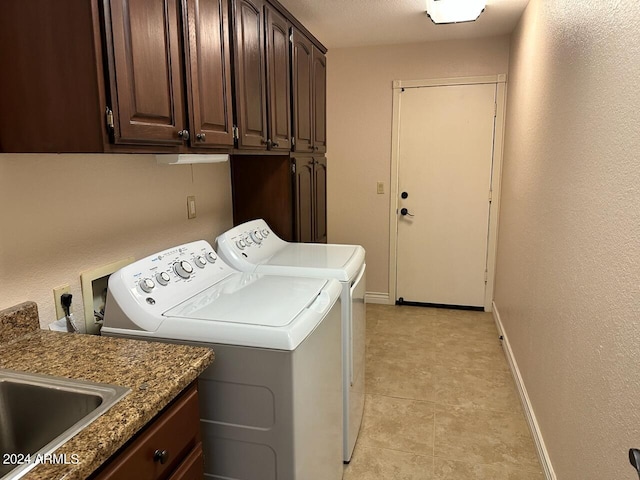 clothes washing area with light tile patterned floors, cabinets, and washer and clothes dryer