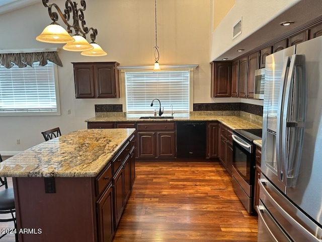 kitchen with sink, a kitchen bar, dark hardwood / wood-style flooring, hanging light fixtures, and stainless steel appliances