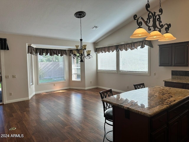 dining area featuring dark wood-type flooring, vaulted ceiling, a textured ceiling, and an inviting chandelier