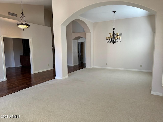 unfurnished room with lofted ceiling, a chandelier, and wood-type flooring