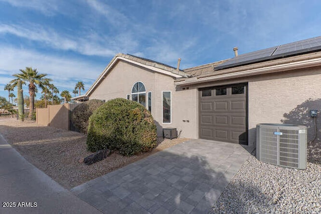 view of side of home with a garage, solar panels, and central air condition unit