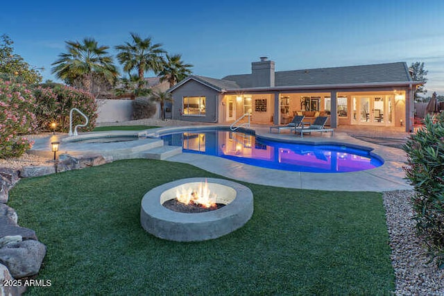 pool at dusk with an in ground hot tub, a patio area, and an outdoor fire pit