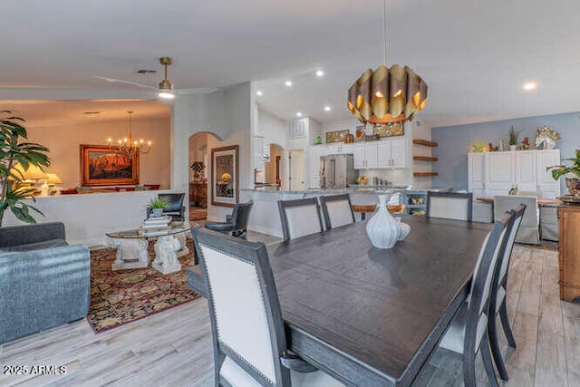 dining room with ceiling fan with notable chandelier and light wood-type flooring