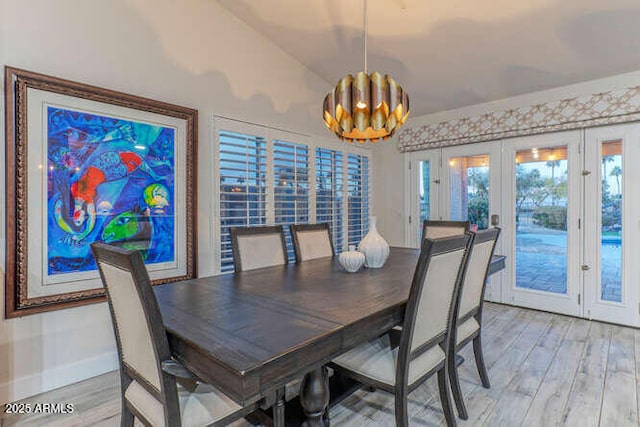 dining space with french doors, a chandelier, and light wood-type flooring