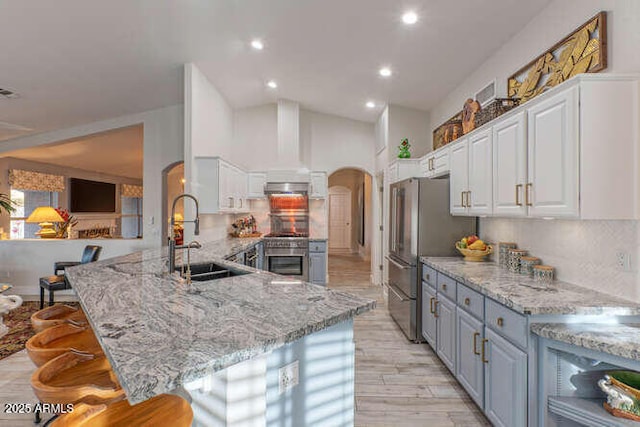 kitchen featuring sink, stainless steel refrigerator, backsplash, white cabinets, and a kitchen bar