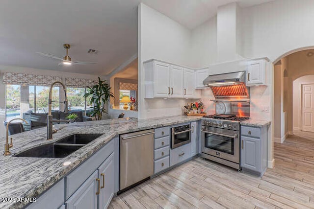 kitchen featuring sink, white cabinetry, light stone counters, light wood-type flooring, and stainless steel appliances