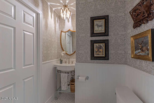 bathroom with toilet and a notable chandelier