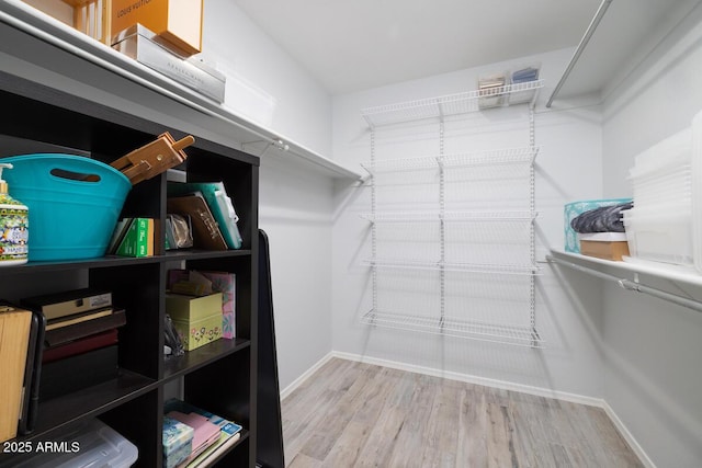 walk in closet with light hardwood / wood-style floors