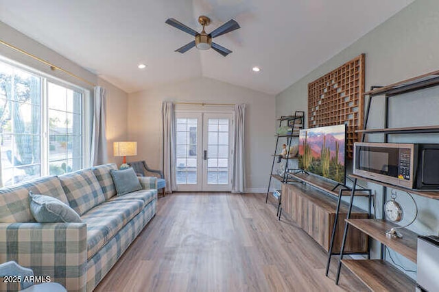 living room with lofted ceiling, light hardwood / wood-style flooring, french doors, and ceiling fan