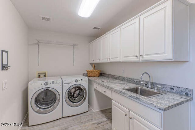 washroom featuring light hardwood / wood-style floors, sink, cabinets, and independent washer and dryer