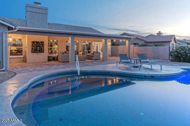 pool at dusk featuring outdoor lounge area and a patio area