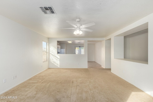 spare room featuring ceiling fan, light carpet, and a textured ceiling