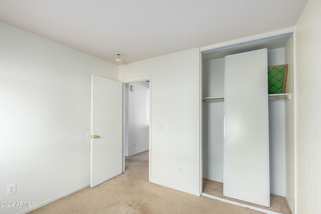 unfurnished bedroom with light colored carpet and a closet