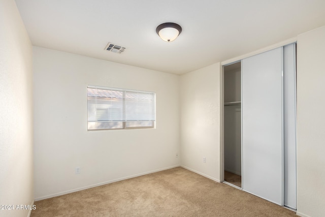 unfurnished bedroom with light carpet and a closet