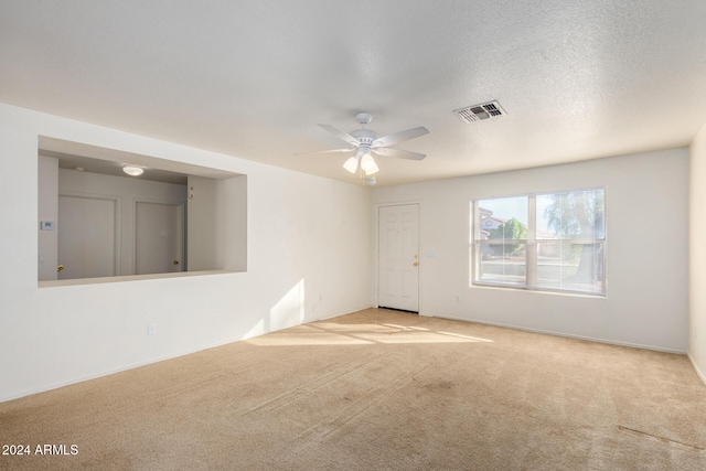 unfurnished room featuring ceiling fan, light colored carpet, and a textured ceiling