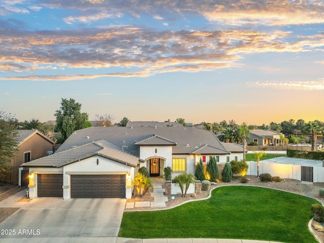 view of front of home with a tile roof, a lawn, stucco siding, a garage, and driveway