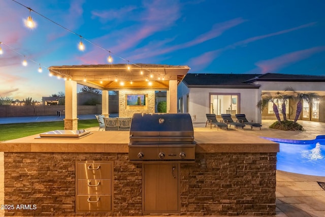 view of patio with exterior kitchen and a grill