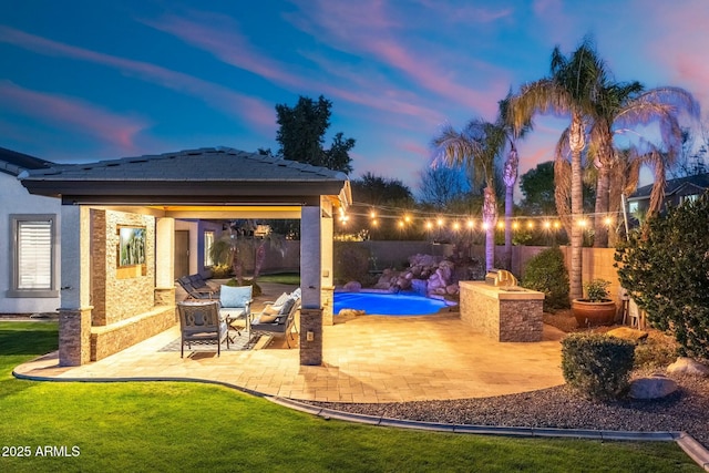 patio terrace at dusk featuring a yard, a fenced in pool, and a fenced backyard