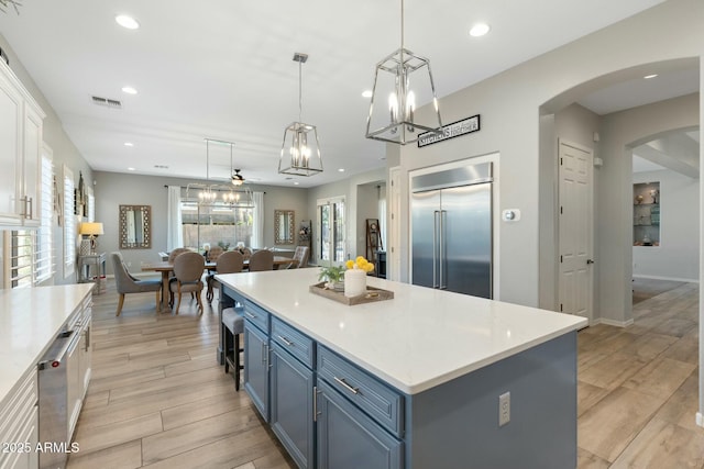 kitchen with visible vents, blue cabinetry, built in fridge, light countertops, and wood tiled floor