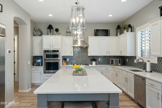 kitchen featuring a sink, appliances with stainless steel finishes, light wood-style flooring, and white cabinetry
