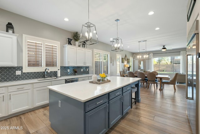 kitchen with decorative backsplash, white cabinets, stainless steel dishwasher, and a sink