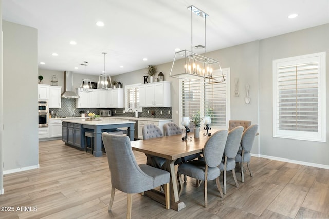 dining room featuring light wood finished floors, a notable chandelier, recessed lighting, a toaster, and baseboards