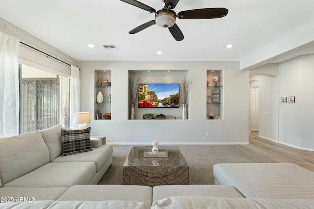 living area featuring visible vents, built in shelves, arched walkways, and baseboards