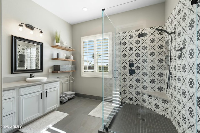 bathroom with tile patterned floors, baseboards, a stall shower, and vanity