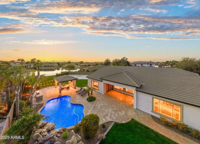 pool at dusk with a gazebo, a patio area, an outdoor pool, and a fenced backyard