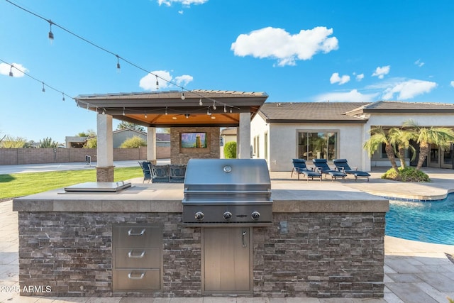 view of patio / terrace featuring a gazebo, exterior kitchen, area for grilling, and a fenced in pool