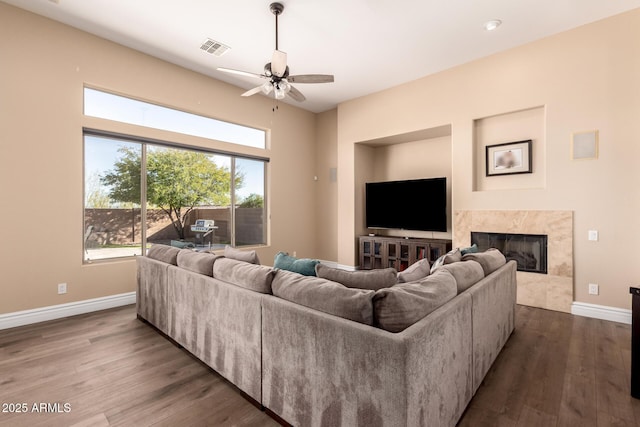 living room featuring hardwood / wood-style flooring, ceiling fan, and a premium fireplace