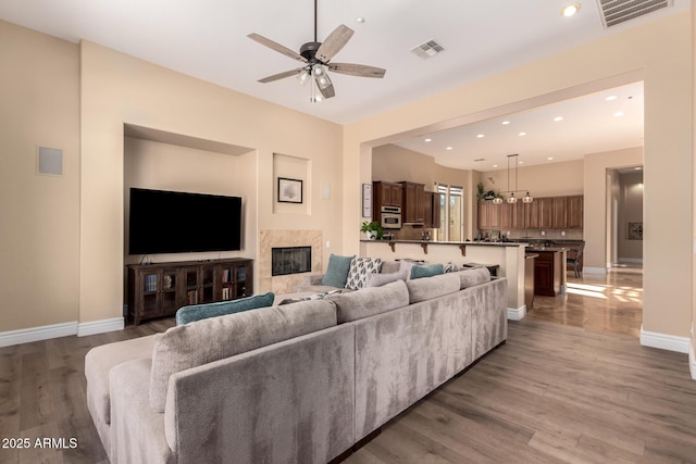 living room featuring ceiling fan, a fireplace, and dark hardwood / wood-style flooring