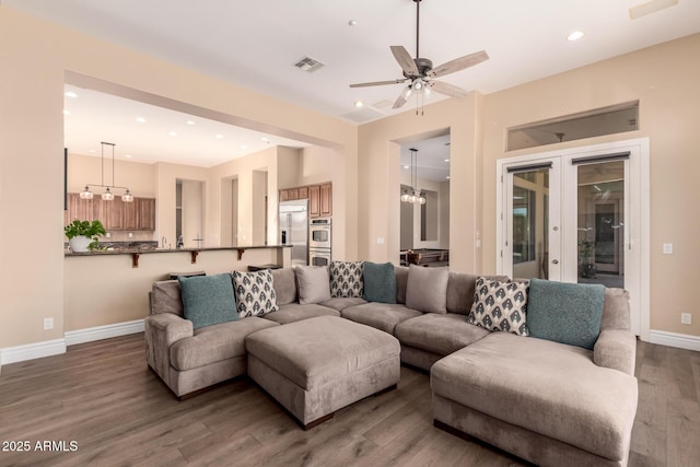 living room featuring french doors, dark hardwood / wood-style floors, and ceiling fan with notable chandelier