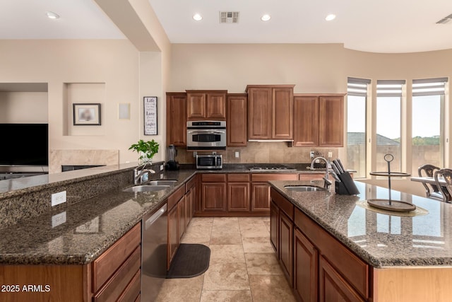 kitchen with stainless steel appliances, kitchen peninsula, sink, and dark stone countertops