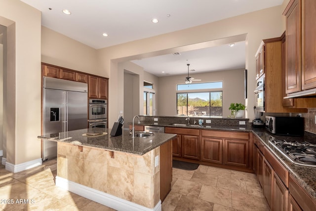 kitchen featuring a kitchen island with sink, sink, a breakfast bar area, and dark stone counters