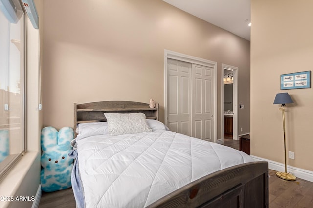 bedroom with ensuite bathroom, dark wood-type flooring, and a closet